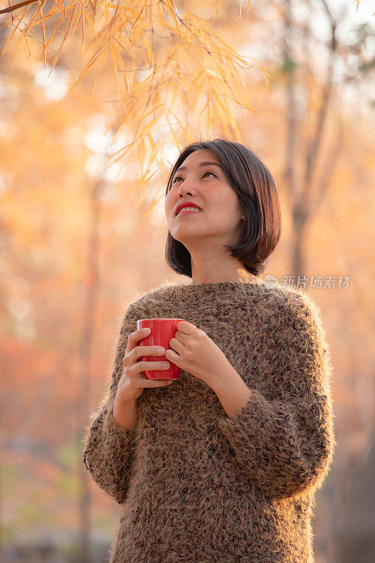 亚洲女人在冬天早上喝热茶或咖啡。