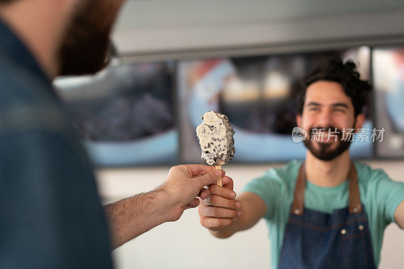 在冰淇淋店里，一名男服务员正在给一对夫妇端冰淇淋
