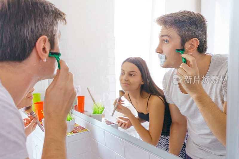 年轻人刮胡子，妻子对着镜子化妆
