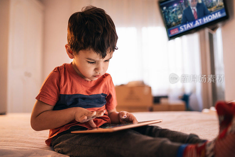 小男孩在隔离期间在家里玩平板电脑和游戏