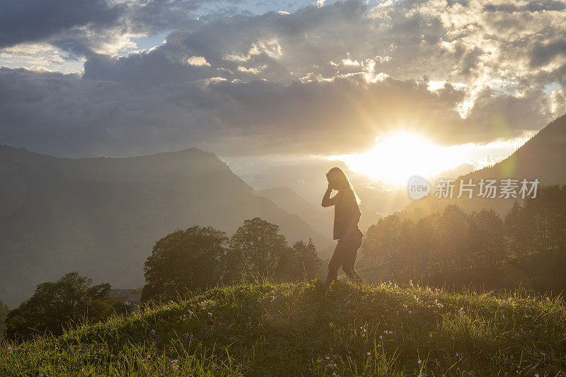 日出时分，女性徒步旅行者在高山草甸中放松