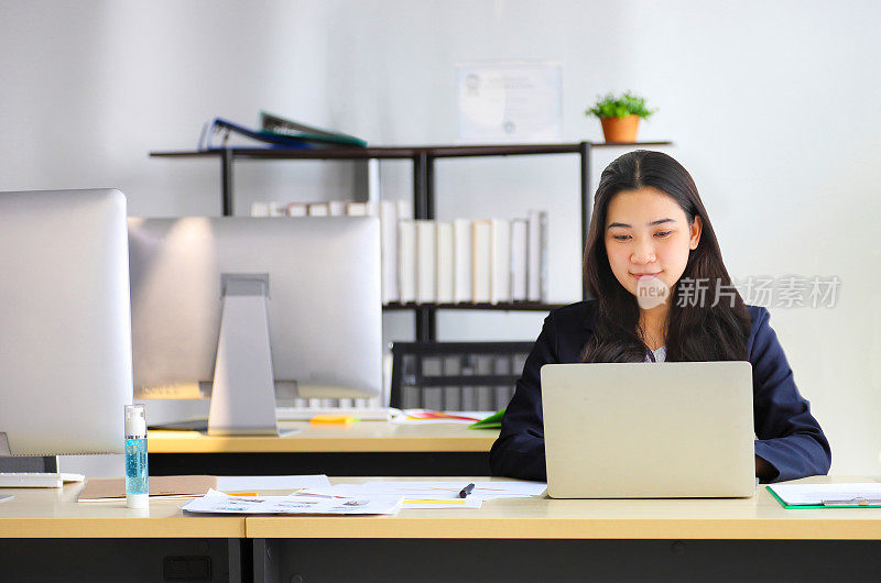 穿着正装在办公室使用笔记本电脑的亚洲女商人