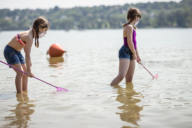 快乐的年轻女孩在当地的河里用渔网捕鱼