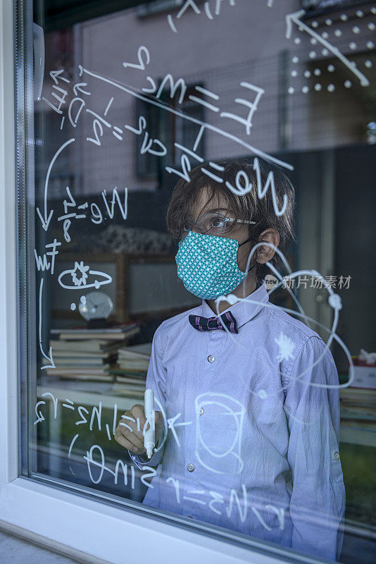 戴着口罩的天才男孩在窗户上写公式。