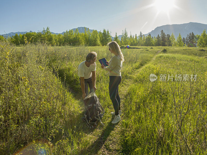 徒步旅行的夫妇沿着小路穿过绿色的山地草地