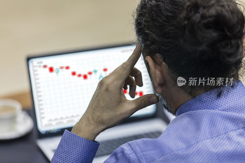 集中交易者在笔记本电脑上观察下跌的股票交易图表