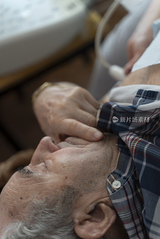医护护士使用便携式超声机在家为97岁的老年男性患者进行超声心脏健康检查。