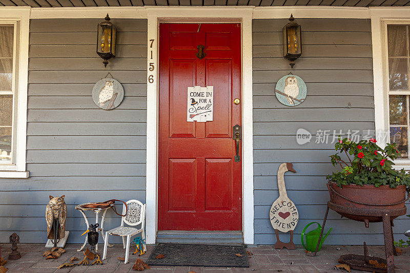 位于历史小镇的殖民时代房屋入口。红色的门上有一个标志，上面写着:请进，因为上面有一个女巫符号