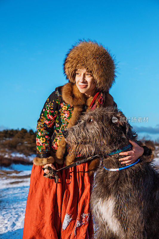 美丽的年轻俄罗斯女人在外面的雪和她的狗在荷兰乡村