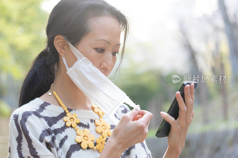 美丽的日本女人用智能手机和面具