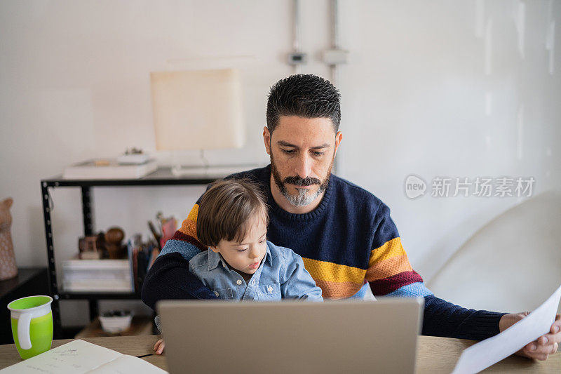 在家里工作的成熟男人带着年幼的儿子——有特殊需要的儿子