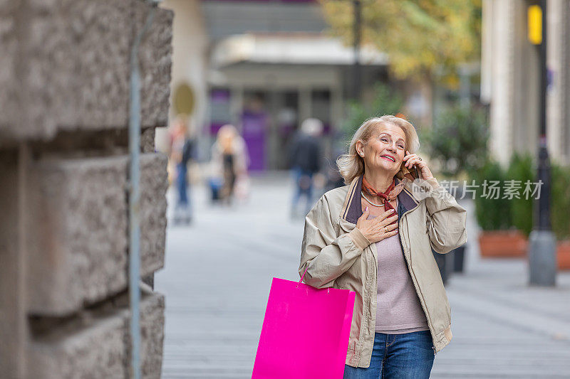 一位上了年纪的妇女在匆忙中使用手机，同时走在城市街道上。