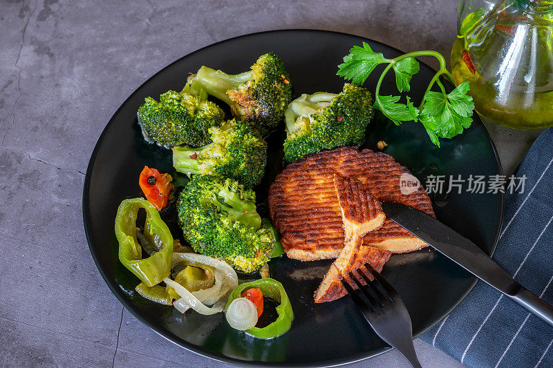 健康饮食:三文鱼排配花椰菜和蔬菜。黑色盘子上的蔬菜三文鱼片。家常菜、健康节食的生活理念。