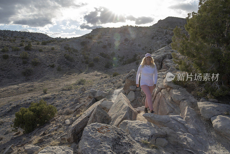 清晨，一名女子沿着沙漠小径徒步旅行