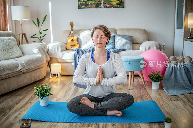 一个在公寓里练习瑜伽的女人，过着健康平和的生活。