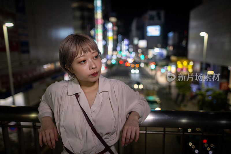 年轻女子晚上在人行桥上休息