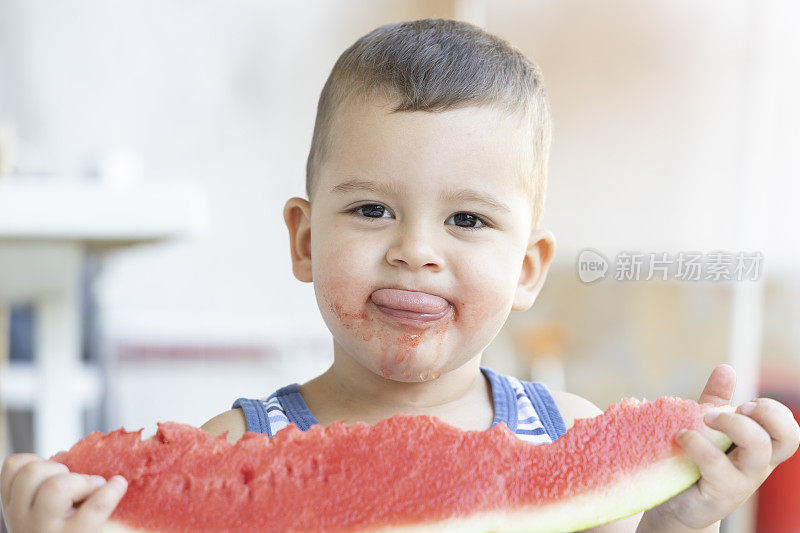 小可爱的男孩在外面的花园里吃西瓜。夏天的乐趣和健康的食品，为年轻的孩子。