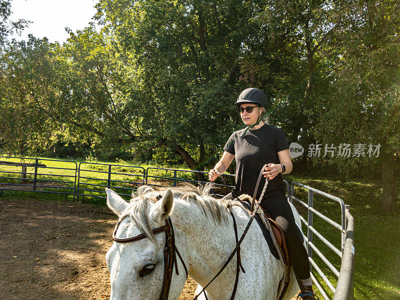 一个成熟的女人在围场里骑马