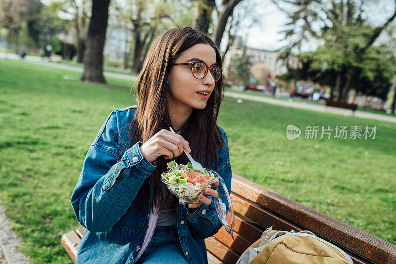 一个美丽的学生在公园里吃午饭