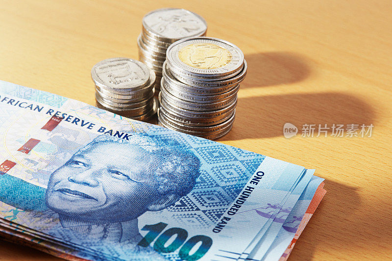 一堆南非硬币旁边是一堆描绘纳尔逊·曼德拉的钞票