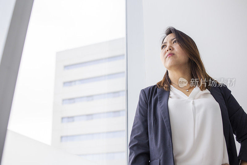 一个日本女人从办公室的窗户往外看