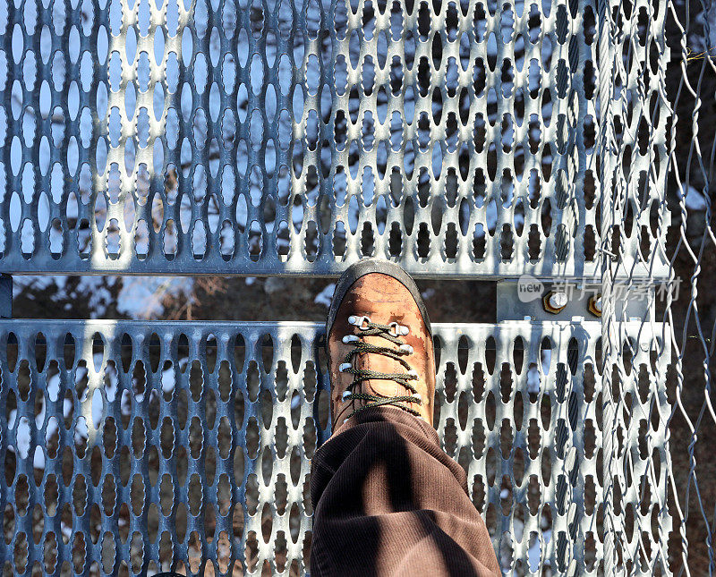 在吊桥上行走的人的轻便靴子