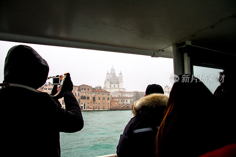 游客们在船上旅行，并拍照到威尼斯的水平照片天气是雨天