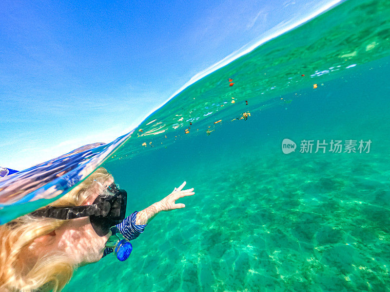一名女子戴着水肺护目镜在碧绿的海洋中潜泳