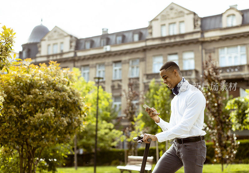 年轻的非洲裔美国人在街上骑着电动车玩手机