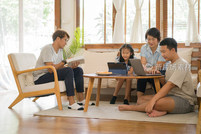 家人在客厅放松的同时使用平板电脑和笔记本电脑。