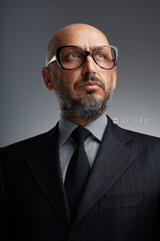 工作室肖像中年大胡子商人与有趣的眼镜在一个黑暗的背景摆姿势