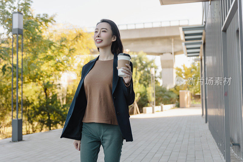 成功的女经理走在城市的街道上。