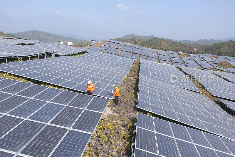 两个亚洲男性工程师在太阳能发电厂前讨论