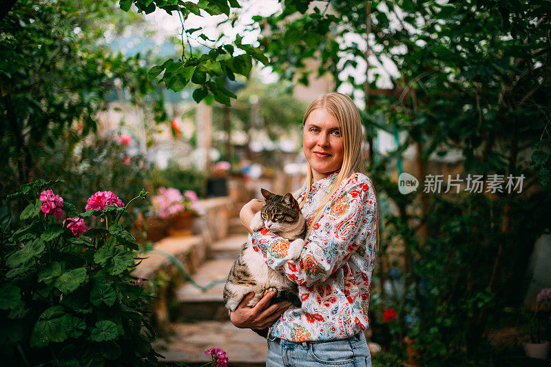 年轻女子爱她的猫在花园里