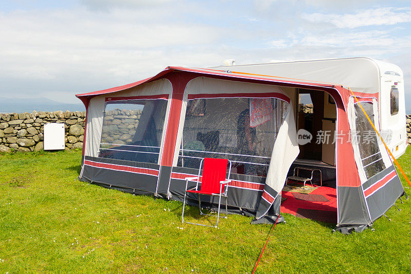 房车和遮阳篷在威尔士乡村度假，家外之家的家人享受户外生活一段时间。