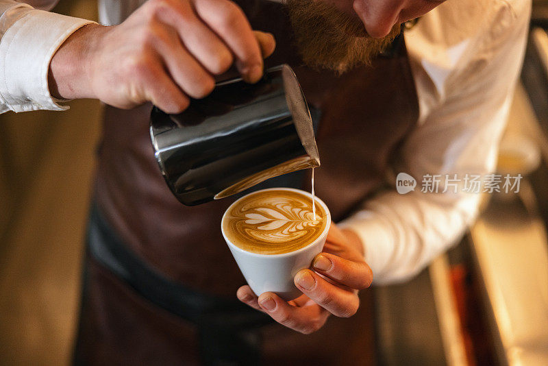 一位才华横溢的白人男咖啡师用拉花艺术小心翼翼地制作咖啡