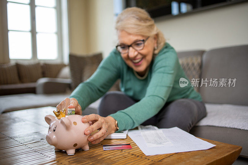 快乐的老年妇女在存钱罐里存钱