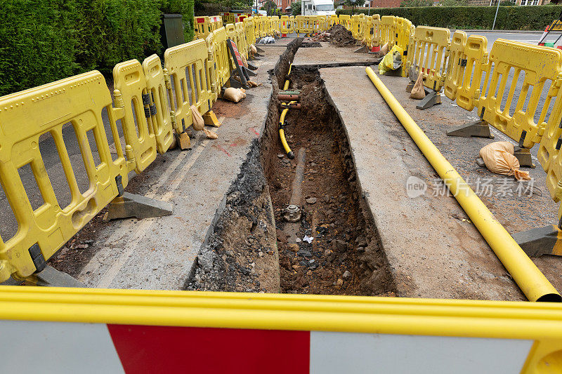 英国的道路工程正在挖掘当地的柏油路面，以修复地下的公用管道，并设置安全屏障和标志