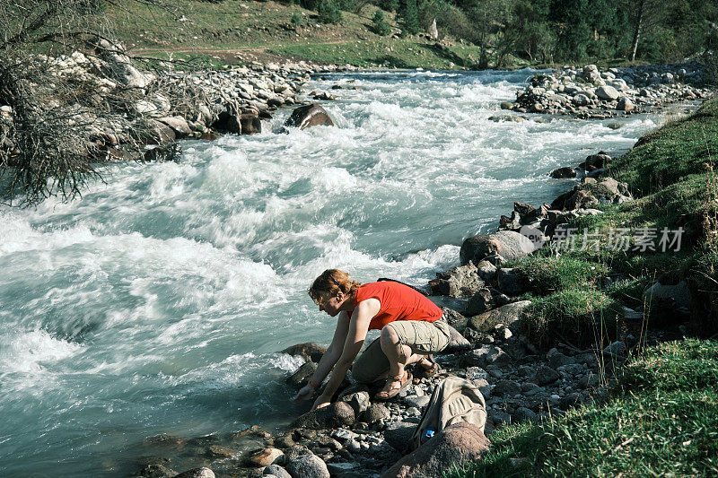 女游客在山河中洗手
