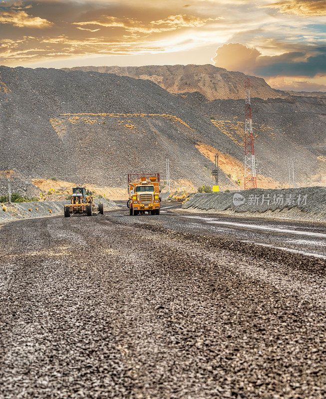 露天钻石矿，采矿平地机和除尘车维护通往矿坑的砾石土路
