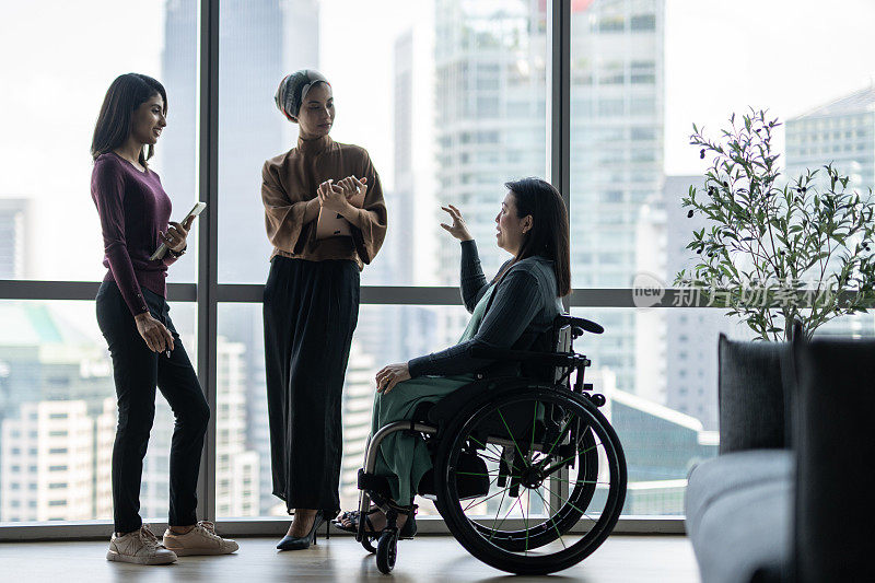 女同事正在和一个坐轮椅的女人讨论