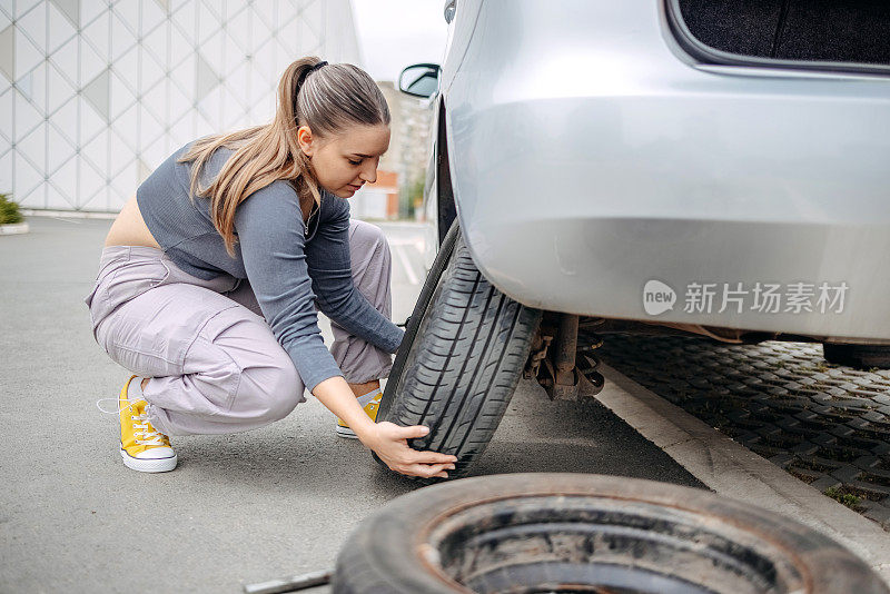 女人在给她的汽车换爆胎