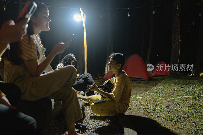 一群朋友在晚上露营时玩吉他