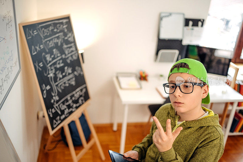 十几岁的男孩在家里努力学习，用数码平板电脑计算