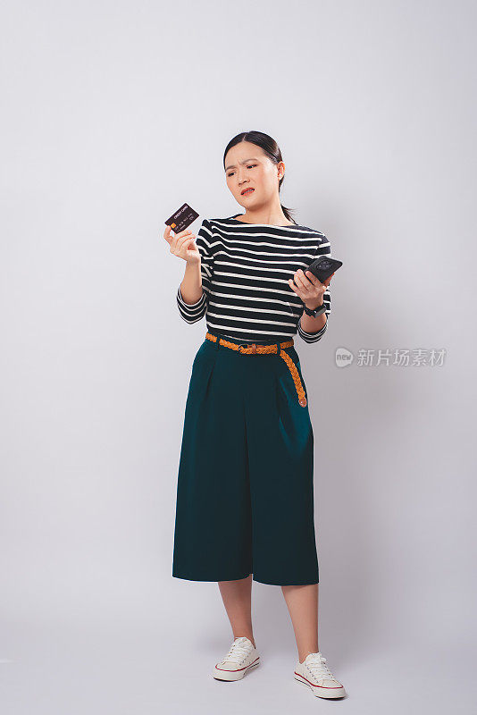 使用智能手机持有信用卡的亚洲女性在网上购物和支付时存在问题，孤立在白色背景下。