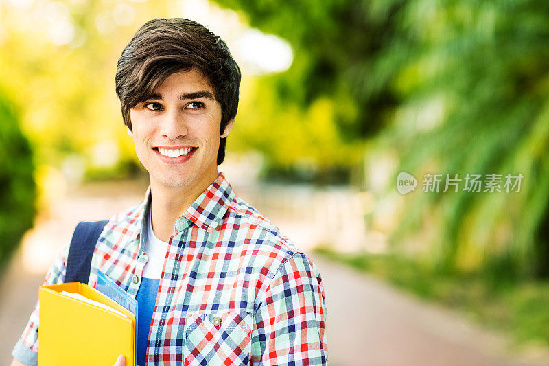 在大学校园里拿着文件的男学生