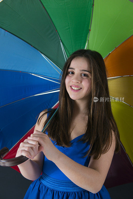 带彩虹伞的小女孩在黑色背景上
