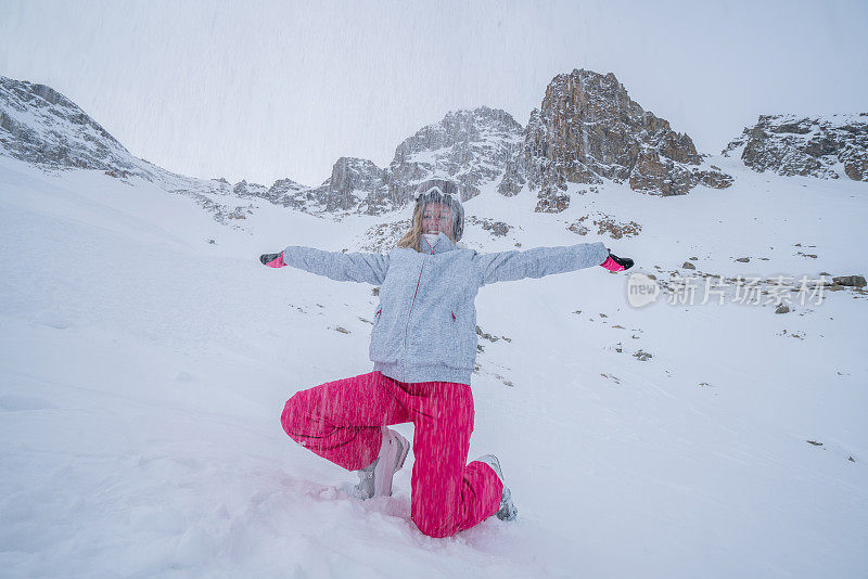 年轻女子在滑雪坡上伸开双臂