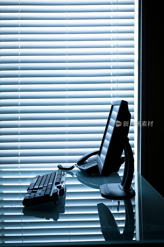剪影的办公桌与电脑和电话。窗口的背景