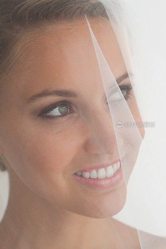 一个浪漫的新娘在面纱后面微笑的特写
